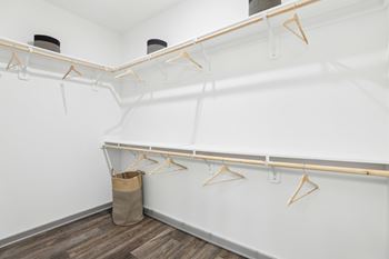 A white closet with wooden hangers and a brown bag on the floor. at The Junction at Rockledge Apartments, Florida